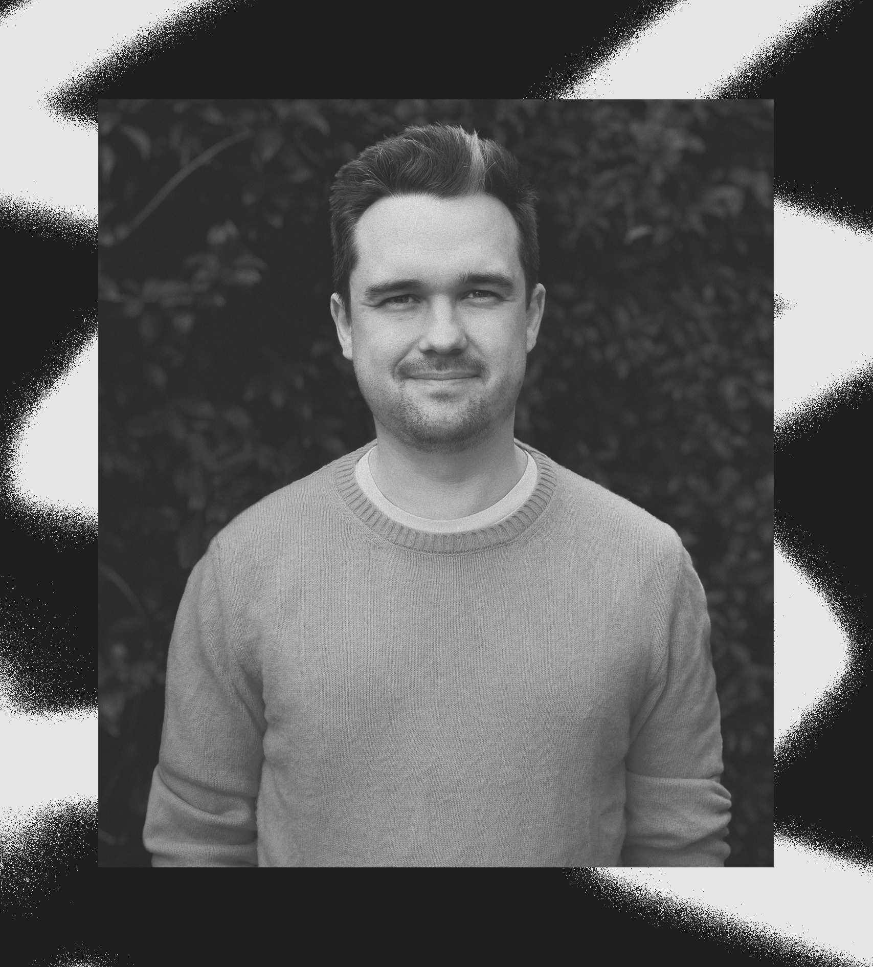 A picture of Elliot Midson wearing a yellow jumper in front of a green hedge