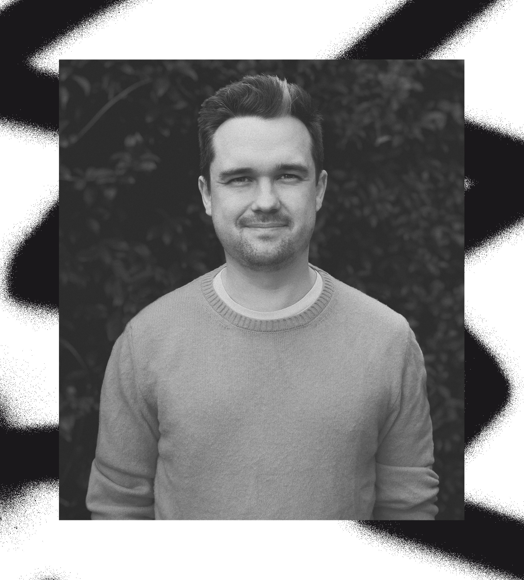A picture of Elliot Midson wearing a yellow jumper in front of a green hedge